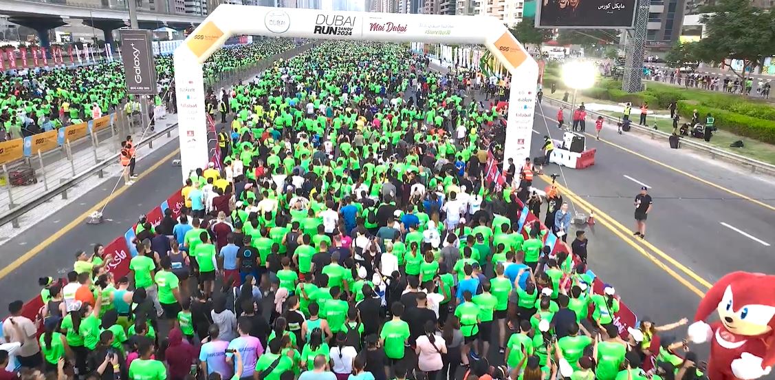 Large crowd at the Dubai Police Run 2024 marathon event in Dubai, participants wearing green shirts.